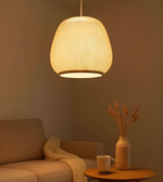 Woven pendant light hanging above a cozy living room setup with a sofa and table.