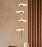 Modern pendant light fixture against a beige wall with a brown curtain.