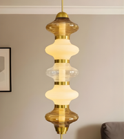 Decorative pendant light with gold accents and glass shade against a neutral wall.