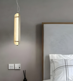 Modern pendant light fixture hanging above a bed in a bedroom setting.
