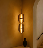 Decorative pendant light fixture casting a warm glow in a room with a vase on a ledge.