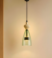 Modern pendant light with green glass shade on a beige background