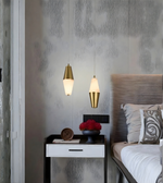Modern bedroom with gold pendant lights, nightstand, and bed.