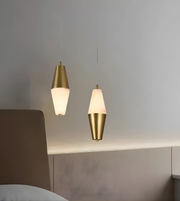 Two gold pendant lights hanging above a bed with a neutral background