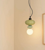 Green pendant light hanging against a beige wall