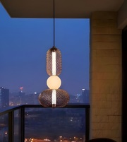 Modern pendant light fixture on a balcony with city skyline view at night