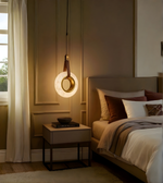 Modern bedroom with a pendant light, bed, and side table.