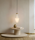 Modern pendant light hanging above a round wooden table with a vase and book in a minimalistic room.