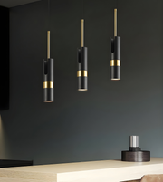 Modern pendant lights with black and gold design hanging against a dark wall.