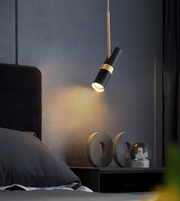 Modern pendant light fixture in a bedroom setting with decorative items on a nightstand.