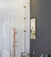 Coat rack against a white curtain with a gray wall and framed picture in the background