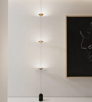 Modern pendant light fixture on a neutral wall with a framed abstract art piece.