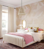 Neatly made bed with pink blanket and pillows in a bedroom with patterned wallpaper.