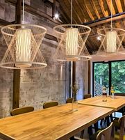 Modern interior with wooden tables and chairs, and three hanging wire pendant lights.