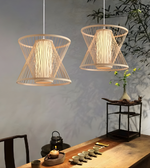 Two woven pendant lights hanging above a wooden table with tea set and decorative items.