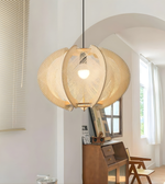 Woven pendant light fixture in a room with a desk and window.