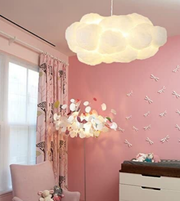 Children's room with pink walls, cloud-shaped ceiling light, and decorative elements.