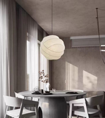Modern dining room with a round table and chairs, featuring a large pendant light.
