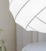 Close-up of a white lampshade with black trim against a neutral background