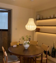 Dining room with a round wooden table, chairs, and a hanging light fixture.