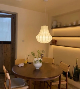Dining room with a round wooden table, chairs, and a hanging light fixture.