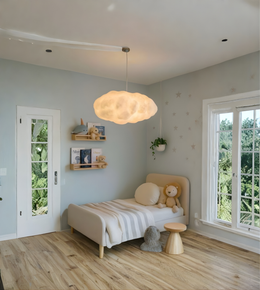 Children's bedroom with a bed, teddy bear, and cloud-shaped pendant light.
