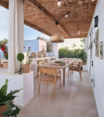 Outdoor dining area with wooden tables and chairs, plants, and a wooden ceiling.