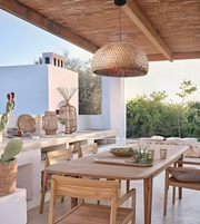 Outdoor dining area with wooden table and chairs under a wooden pergola.