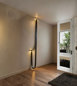 Modern wall light fixture on a neutral wall in a room with a door and plants.