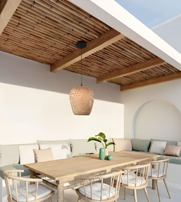 Modern outdoor dining area with wooden table and chairs, wicker lampshade, and white walls.