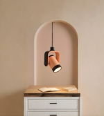 Modern pendant light with a wooden shade on a desk against a beige wall.