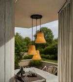 Woven pendant lights hanging over a table with a view of greenery outside.