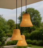 Three woven pendant lights hanging outdoors with a blurred natural background