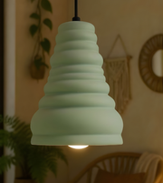 Green pendant light hanging in a room with plants and wall decor.