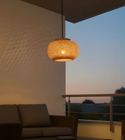 Woven pendant light hanging above a sofa on a balcony at dusk.