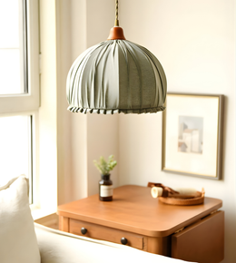 Green pendant lamp hanging above a wooden desk with a window in the background