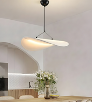 Modern pendant light hanging above a dining table with a vase of flowers.