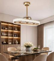 Luxury oval crystal fan chandelier with gold finish installed above a modern dining table