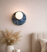 Blue marble disc wall light with glowing frosted globe in modern bedroom