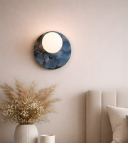 Blue marble disc wall light with glowing frosted globe in modern bedroom