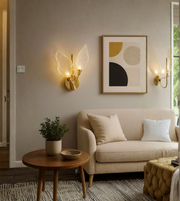 Gold leaf wall sconce mounted in a modern living room with soft ambient lighting