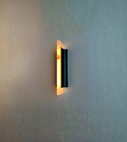 Modern vertical wall sconce with black metal frame and frosted glass diffuser