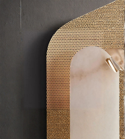 Close-up of perforated gold wall light with soft glowing diffuser
