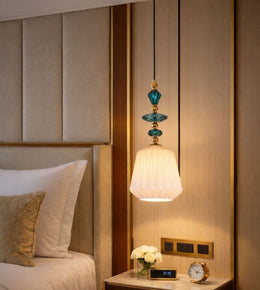 Elegant bedside hanging lamp with teal glass detailing and warm glow