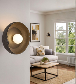 Sculptural crater wall light with glowing central orb mounted on a modern interior wall
