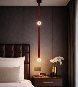 dual ring leather strap pendant light with warm glow hanging beside bed, modern luxury bedroom lighting