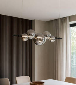 Modern smoky glass globe chandelier with black frame hanging above dining table in contemporary interior