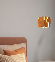 Modern amber geometric cube pendant light with warm glow beside bed in contemporary bedroom