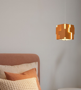 Modern amber geometric cube pendant light with warm glow beside bed in contemporary bedroom