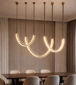 luxury crystal arc chandelier with leather suspension and rose gold finish above dining table, modern elegant lighting